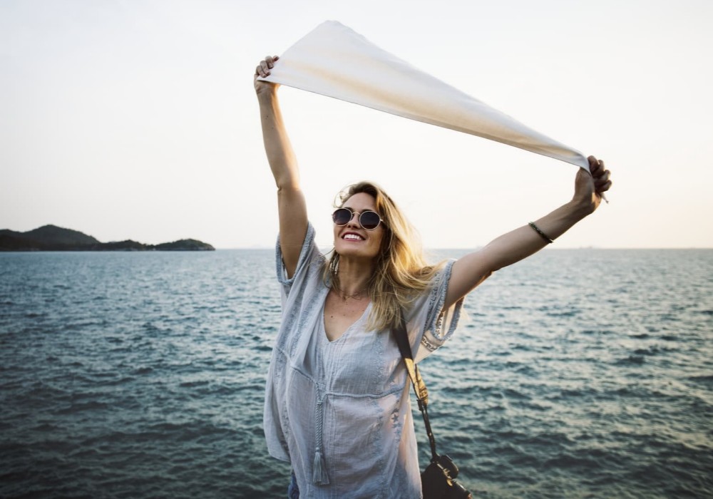 After Choosing SC: A woman outside at the beach celebrating, free from financial anxiety and worry.