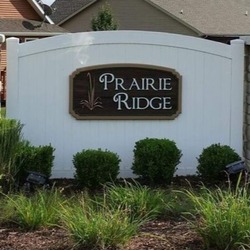 A brown Prairie Ridge sign on a white fence in the Prairie Ridge neighborhood